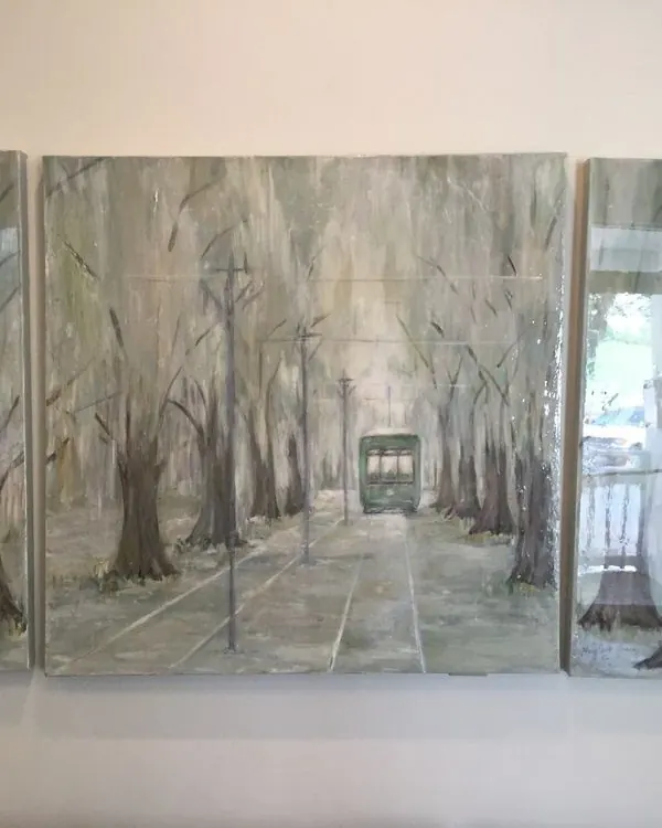 A three-panel painting of a St. Charles Avenue streetcar under the oaks, hanging in the Uptown Dental waiting room.