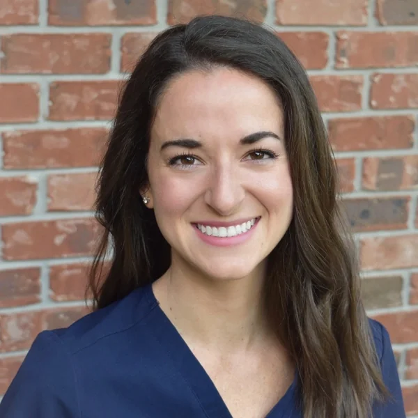 Dr. Julia Daigle, DDS, in navy scrubs.