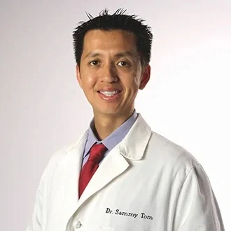 Dr. Sammy Tom, DDS, in his white coat.