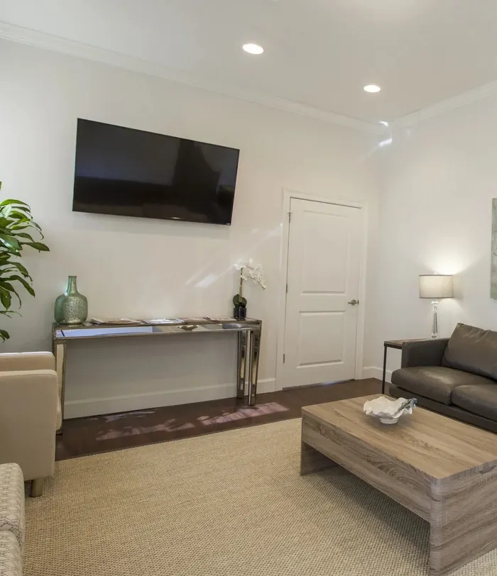 The Uptown Dental waiting room, with a television, a console table and armchairs.